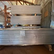 Stock de tôles aluminium argentées sous charpente bois de l'atelier ALUSCAN